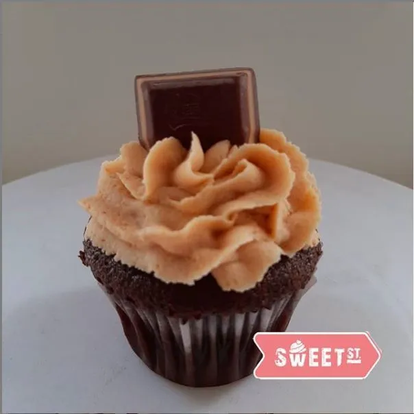 Cupcake de chocolate con crema color caramelo y un trozo de chocolate